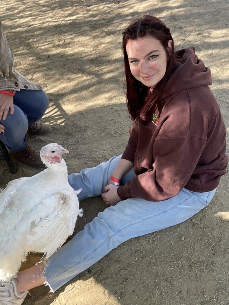 Anya from WhereGalsWander petting a turkey at Gentle Barn